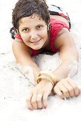 Image showing Attractive brunet woman in red lying on a sand.