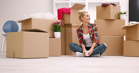 Image showing woman with many cardboard boxes sitting on floor