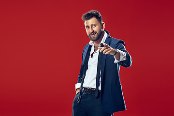 Image showing The happy business man point you and want you, half length closeup portrait on red background.