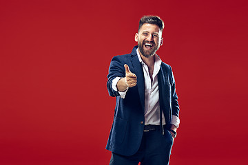 Image showing The happy business man point you and want you, half length closeup portrait on red background.