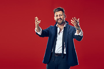 Image showing The happy business man standing and smiling against red background.