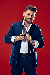 Image showing Businessman tying his tie at red studio