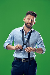 Image showing Businessman tying his tie at green studio