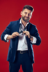 Image showing Businessman tying his tie at red studio