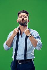 Image showing Male beauty concept. Portrait of a fashionable young man with stylish haircut wearing trendy suit posing over green background.