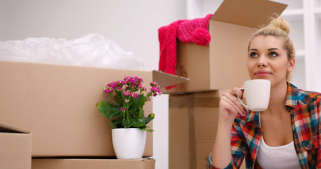 Image showing woman with many cardboard boxes sitting on floor