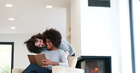 Image showing multiethnic couple hugging in front of fireplace