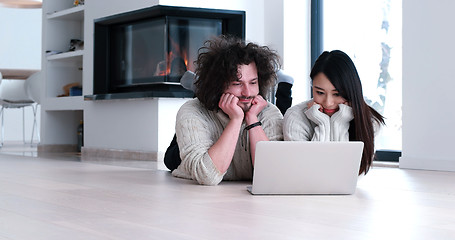 Image showing young multiethnic couple using a laptop on the floor