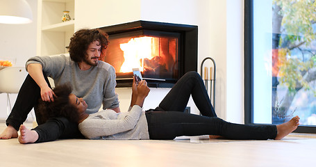 Image showing multiethnic couple using tablet computer on the floor