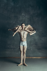 Image showing The young modern ballet dancers posing on gray studio background