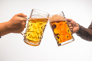 Image showing hands with mugs of beer toasting creating splash isolated on white background