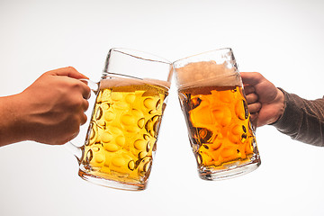 Image showing hands with mugs of beer toasting creating splash isolated on white background