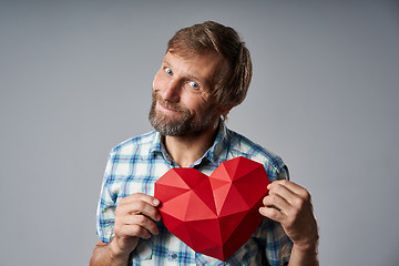 Image showing Smiling mature man in checkered shirt holding heart shape