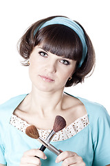 Image showing  Pretty woman in blue dress with two make-up brushes