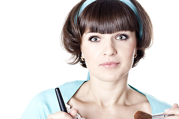 Image showing Attractive brunet woman in blue dress with two make-up brushes