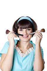 Image showing Attractive brunet woman in blue dress with two make-up brushes