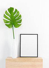 Image showing Tropical leaf in a white vase and black picture frame