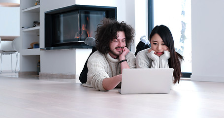 Image showing young multiethnic couple using a laptop on the floor