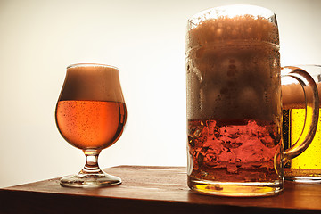 Image showing The two mugs of beer on table background