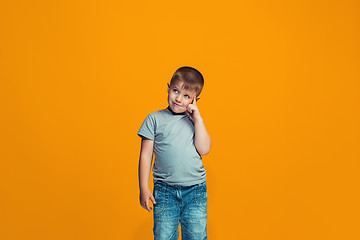 Image showing The happy teen boy standing and smiling against orange background.