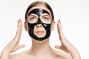 Image showing Young beautiful woman applying a mask for the face of the therapeutic black mud. Spa treatment