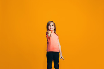 Image showing The happy teen girl pointing to you, half length closeup portrait on orange background.