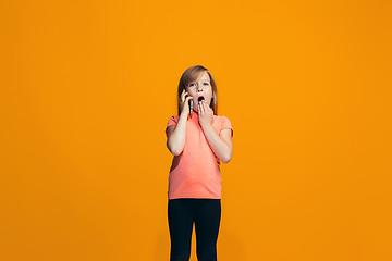 Image showing The happy teen girl standing and smiling against orange background.