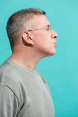 Image showing The serious businessman standing and looking at camera against blue background.