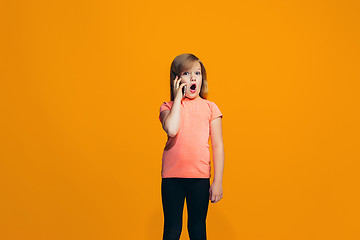 Image showing The happy teen girl standing and smiling against orange background.