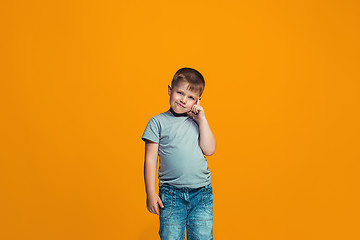 Image showing The happy teen boy standing and smiling against orange background.