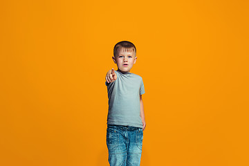 Image showing The happy teen boy pointing to you, half length closeup portrait on orange background.