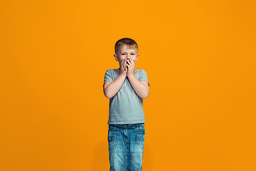 Image showing The happy teen boy standing and smiling against orange background.