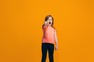 Image showing The happy teen girl pointing to you, half length closeup portrait on orange background.