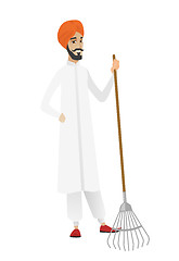 Image showing Young hindu farmer holding gardening rake.