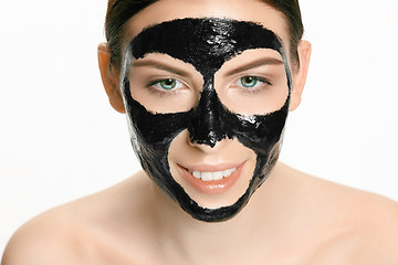 Image showing Young beautiful woman applying a mask for the face of the therapeutic black mud. Spa treatment