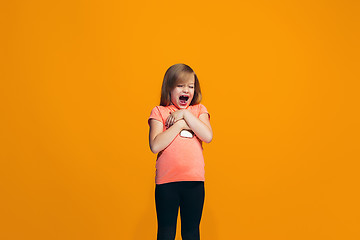 Image showing The happy teen girl standing and smiling against orange background.