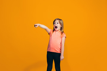 Image showing The happy teen girl pointing to you, half length closeup portrait on orange background.