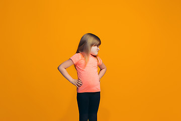 Image showing Portrait of angry teen girl on a orange studio background