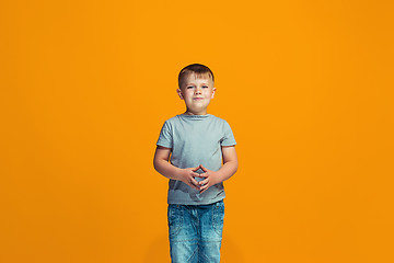 Image showing The happy teen boy standing and smiling against orange background.