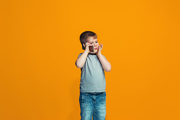 Image showing The happy teen boy standing and smiling against orange background.