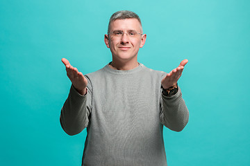 Image showing The happy business man standing and smiling against blue background.