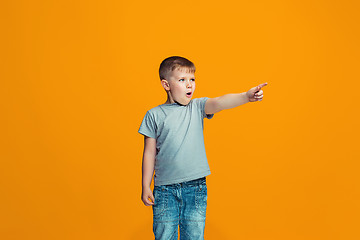 Image showing The happy teen boy pointing to you, half length closeup portrait on orange background.