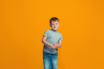 Image showing The happy teen boy standing and smiling against orange background.