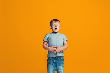 Image showing The happy teen boy standing and smiling against orange background.