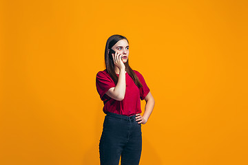 Image showing The happy teen girl standing and smiling against orange background.