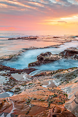 Image showing Ocean flowing into coastal channels eroded into rock and a stunning sunrise