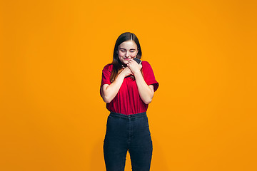 Image showing The happy teen girl standing and smiling against orange background.