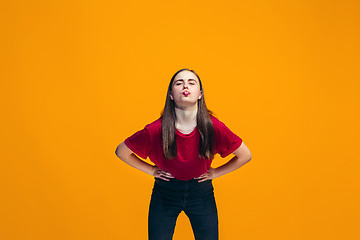 Image showing The happy teen girl standing and smiling against orange background.