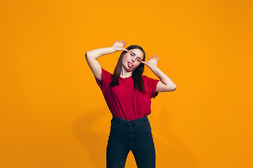 Image showing The happy teen girl standing and smiling against orange background.