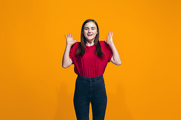 Image showing The happy teen girl standing and smiling against orange background.